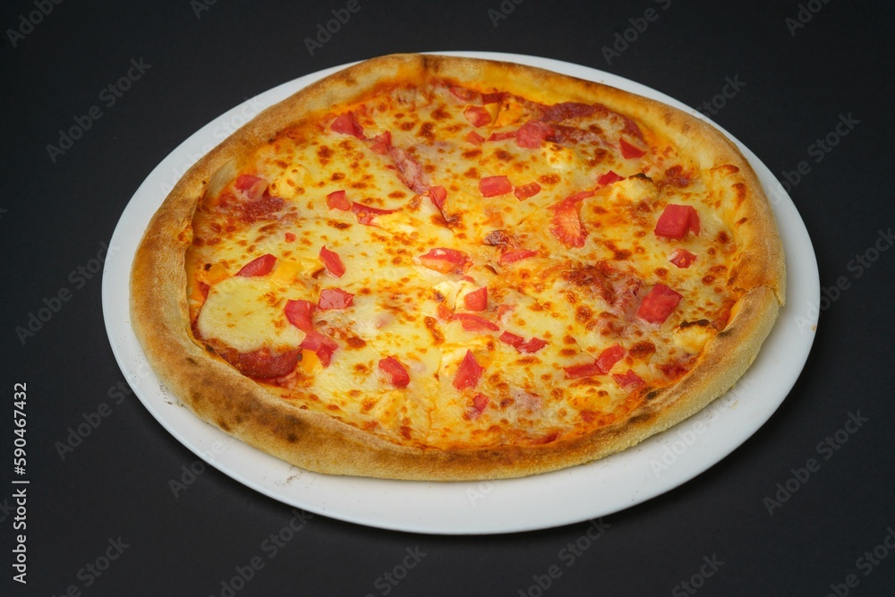 Closeup shot of a pizza Margherita on a white plate placed on a black table