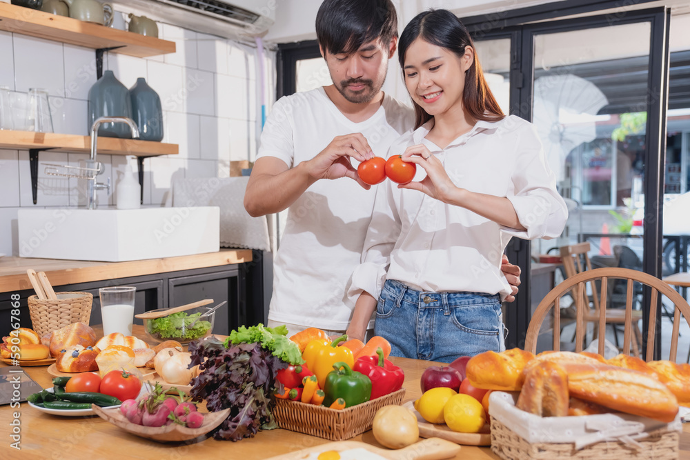 Young Asian couple cooking with fruits and vegetables and using laptop in the kitchen To cook food together within the family happily, family concept. Young Asian couple cooking with fruits and vegetables and using laptop in the kitchen To cook food together within the family happily, family concept.
