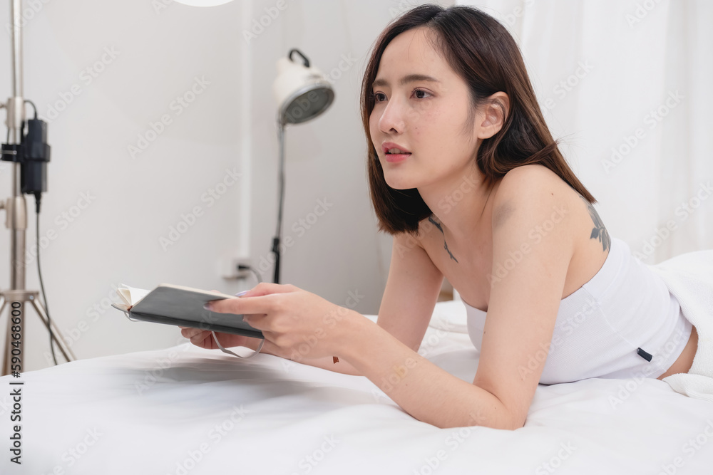 Portrait of white Asian woman with tattoo resting in bed to rest and relax inside white bedroom on her holiday, holiday morning concept. Portrait of white Asian woman with tattoo resting in bed to rest and relax inside white bedroom on her holiday, holiday morning concept.