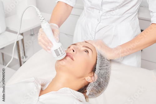 Obraz na plátně Cosmetologist makes cryotherapy for rejuvenation woman face, anti aging cosmetic procedure with in beauty spa salon
