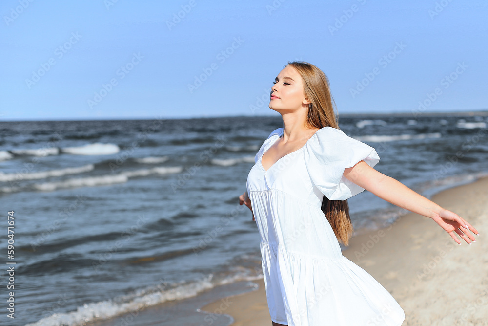 Happy smiling beautiful woman is on the ocean beach in a white summer dress, open arms Happy smiling beautiful woman is on the ocean beach in a white summer dress, open arms