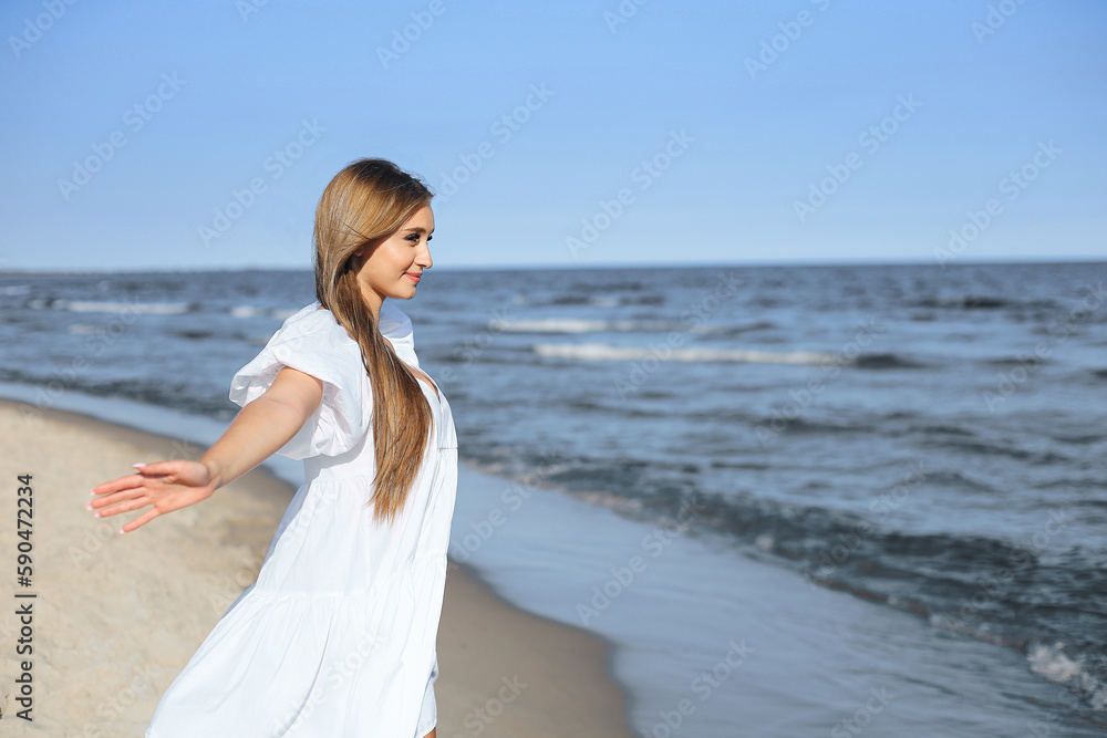Happy, beautiful woman on the ocean beach standing in a white summer dress, open arms Happy, beautiful woman on the ocean beach standing in a white summer dress, open arms