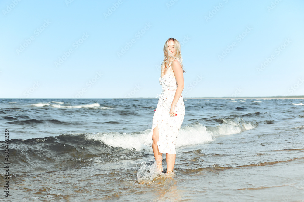 Happy blonde beautiful woman having fun on ocean beach while dancing in waves Happy blonde beautiful woman having fun on ocean beach while dancing in waves