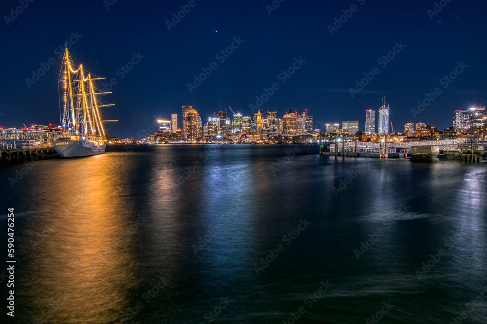 Beautiful view of a sailboat near the cityscape at night