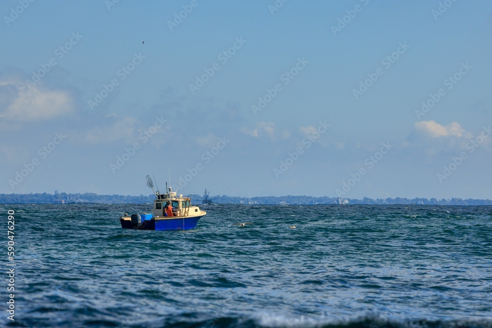 Small fishing boat sailing in an open sea against a blue sky Small fishing boat sailing in an open sea against a blue sky