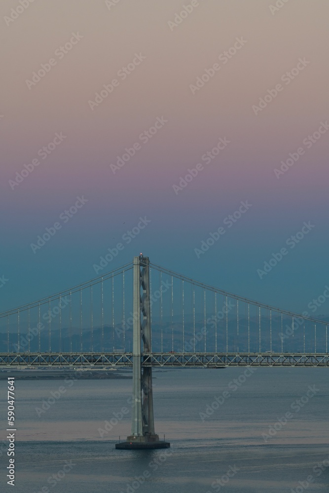 The Oakland Bay Bridge on the water under a pink and blue sky in San Francisco, California The Oakland Bay Bridge on the water under a pink and blue sky in San Francisco, California
