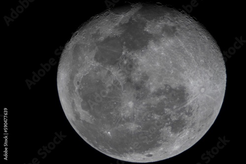 Closeup of the full moon with craters and details of the lunar surface in the dark sky