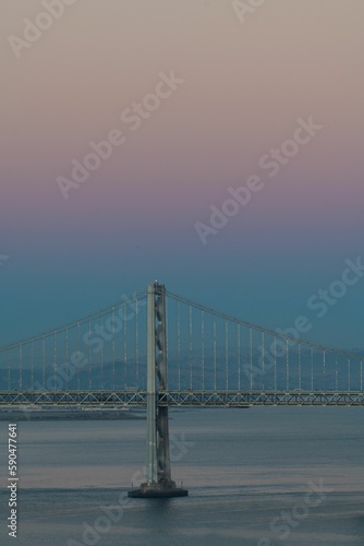 Fototapeta Naklejka Na Ścianę i Meble -  The Oakland Bay Bridge on the water under a pink and blue sky in San Francisco, California