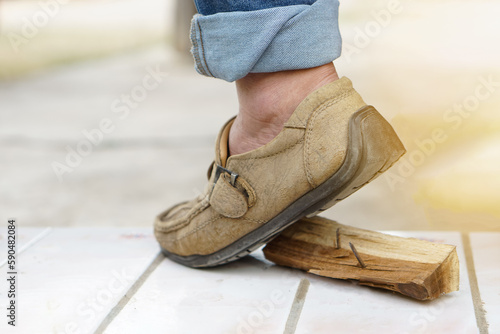 Closeup man wears shoes is stepping on rusty metal nail on wood. Concept, unsafe , risk for dangerous tetanus. Be careful and look around during walking at construction site or risk places. 