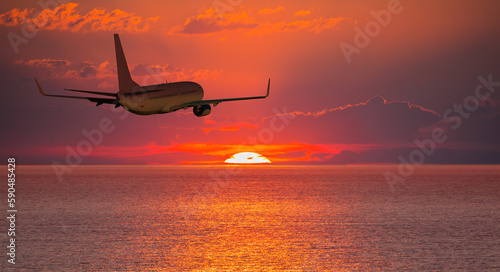 Airplane flying over tropical sea at amazin sunset sky