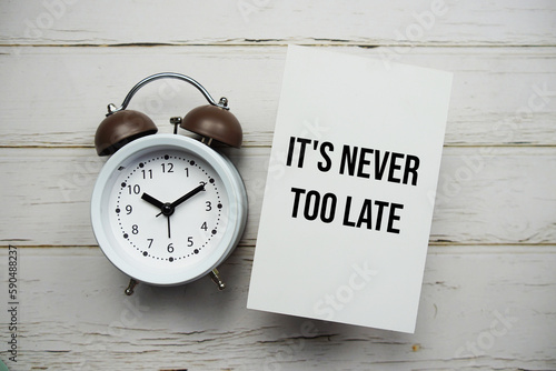 фотографія It's never too late text message with alarm clock top view on wooden background