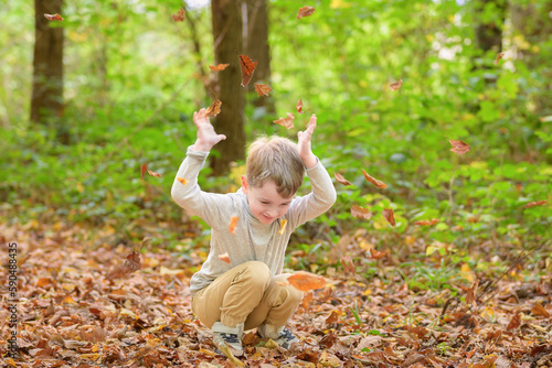 Little happy boy throwing leaves
