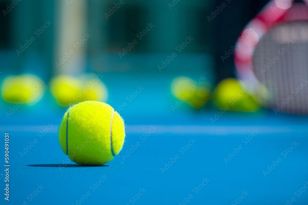 Tennis racket, balls and basket for tennis balls on hard blue court
