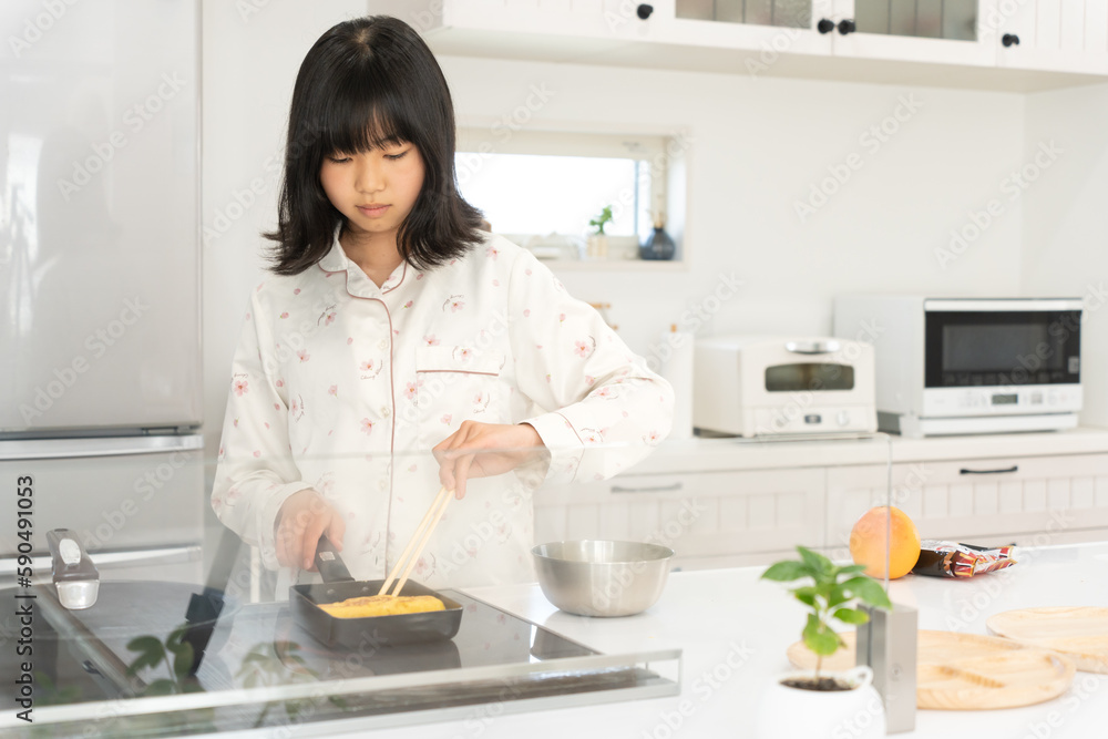 キッチンで料理をするパジャマ姿の日本人の女性