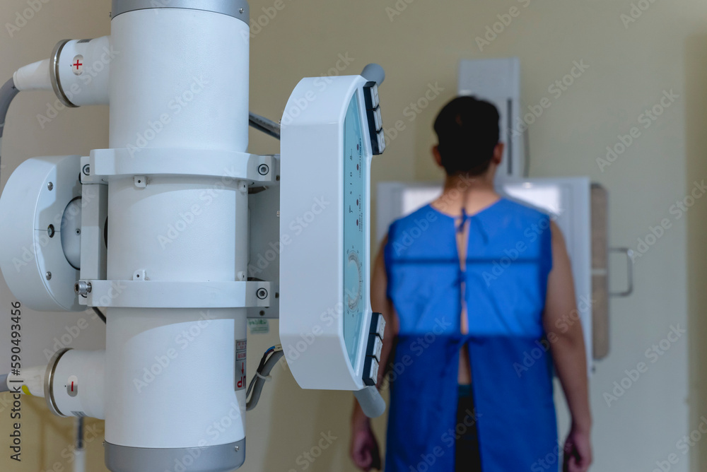 A asian man standing in a medical gown undergoes a chest x-ray ...