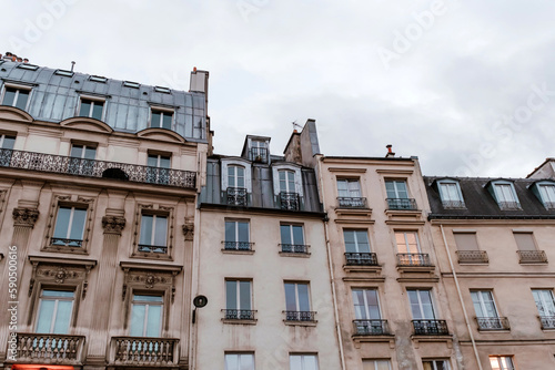 Exterior of aged residential building of beige color with glass windows and beautiful cast iron balconies located in the center of Paris  France