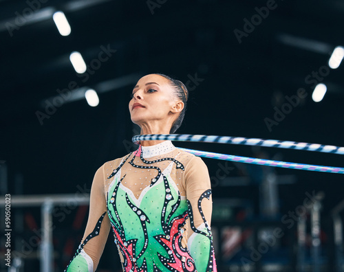 Woman, gymnastics and spinning hoop on neck for competition, sports training and action in arena. Female dancer, rhythmic movement and athlete with loop for dynamic solo concert, event or performance