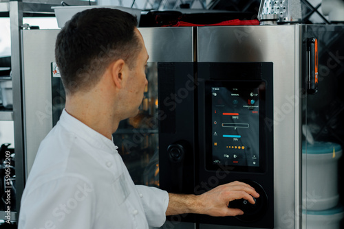 Wallpaper Mural Professional modern kitchen in the restaurant the chef gets out and adjusts the parameters of the oven Torontodigital.ca