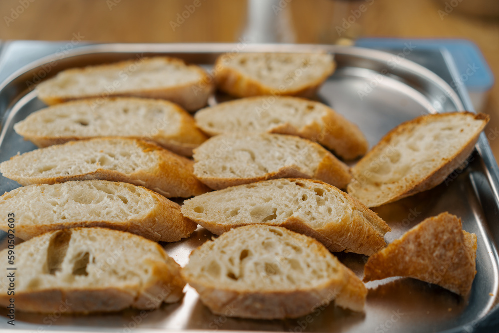 Professional kitchen fresh slices of bread with seasonings lie on a baking sheet close-up of the dish