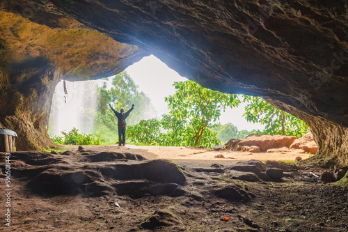 Rear view of a hiker in a cave against the background of Sipi Waterfall in Mount Elgon, Mbale, Uganda photo