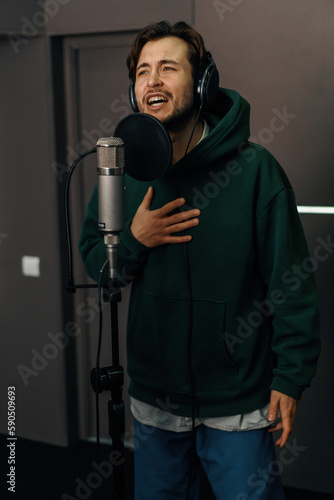 singer with headphones and microphone emotionally recording a new song in a professional recording studio