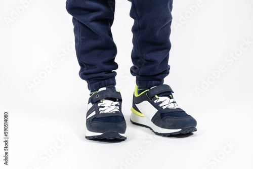 Childrens shoes. Blue kids running shoes sneakers on the legs of a five- or six-year-old boy on a white background.
