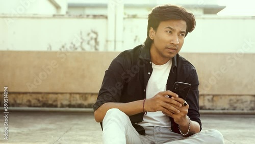 young good looking handsome happy man sitting on the rooftop and doing chat with someone and seems sad