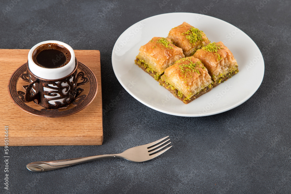 Pistachio baklava on a white plate with Turkish coffee.A plate of traditional baklava on a black background
Pistachio baklava on a white plate with Turkish coffee.A plate of traditional baklava on a black background