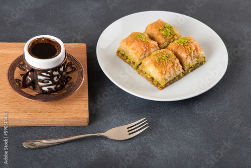 Pistachio baklava on a white plate with Turkish coffee.A plate of traditional baklava on a black background
