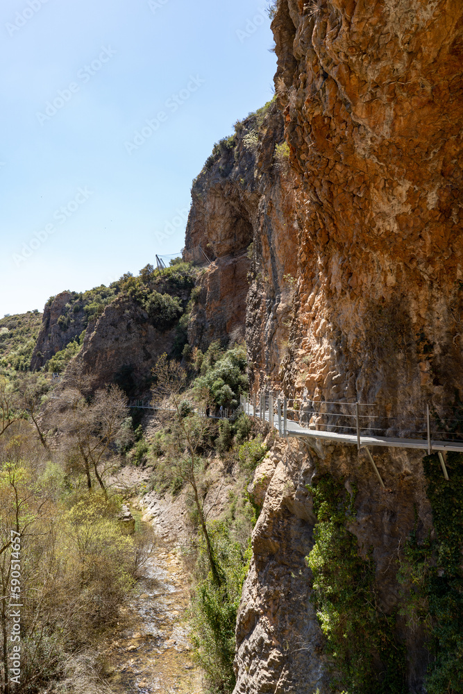 Hanging walkways nailed into the rock that runs inside the Vero river canyon in Alquezar, Aragon, Spain. Hanging walkways nailed into the rock that runs inside the Vero river canyon in Alquezar, Aragon, Spain.