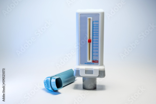 Peak flow meter and a blue inhaler, medical devices for patients with asthma allergy or COPD, light gray background with copy space, selected focus photo