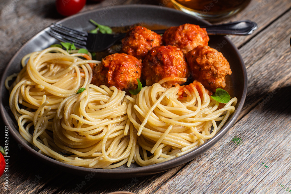 Pasta with meatballs and sauce in a plate on a wooden table Pasta with meatballs and sauce in a plate on a wooden table