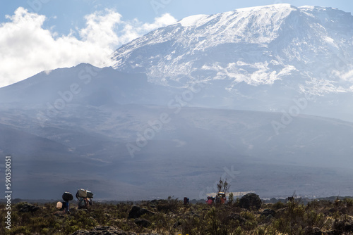 Mount Kilimanjaro with native porters carrying pack on their heads