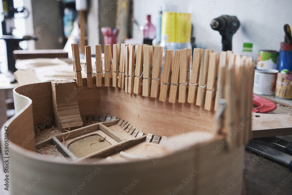 close-up of the body of a guitar under construction with clamps that improve the adhesion of the glue. close-up of the body of a guitar under construction with clamps that improve the adhesion of the glue.