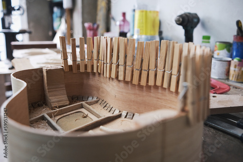 Obraz na plátně close-up of the body of a guitar under construction with clamps that improve the adhesion of the glue