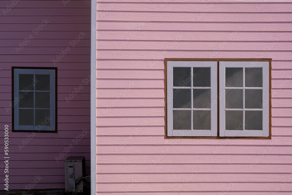 Fototapeta premium Sunlight on surface of Glass and Wooden Windows on artificial wood Wall of Pastel pink House in Vintage style , front view with copy space