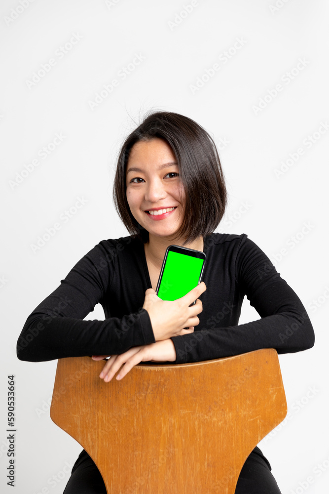 Young beautiful Chinese or Asian girl sitting in a black dress esu white background while looking straight into the camera. Young beautiful Chinese or Asian girl sitting in a black dress esu white background while looking straight into the camera.