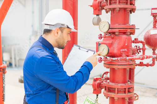 The engineer is inspecting the safety equipment on the fire extinguishing system.The system engineer is checking the pressure and recording it with Clipboard or checking .