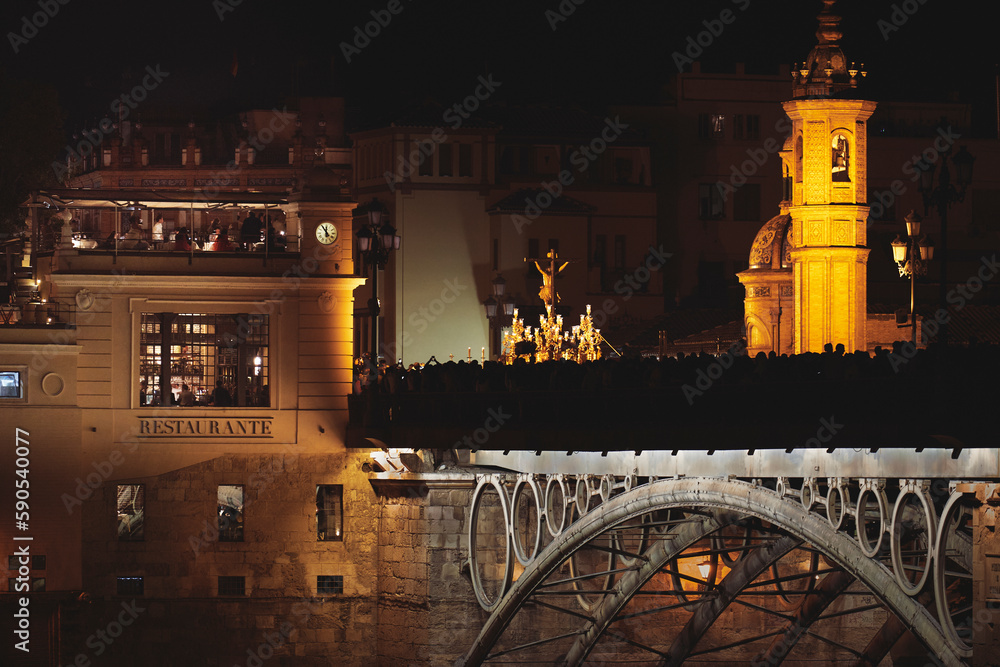 Naklejka premium El Cachorro entrando en su barrio de noche. El cachorro en el Puente de Triana. Triana bridge. Very famous religious image.