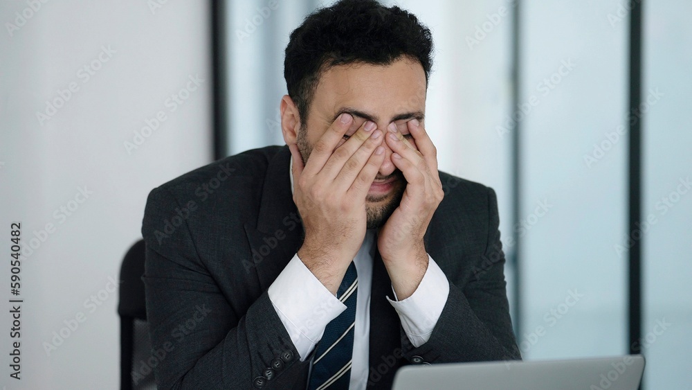 Indian businessman in a suit being worried and irritated after receiving news about work at office Indian businessman in a suit being worried and irritated after receiving news about work at office