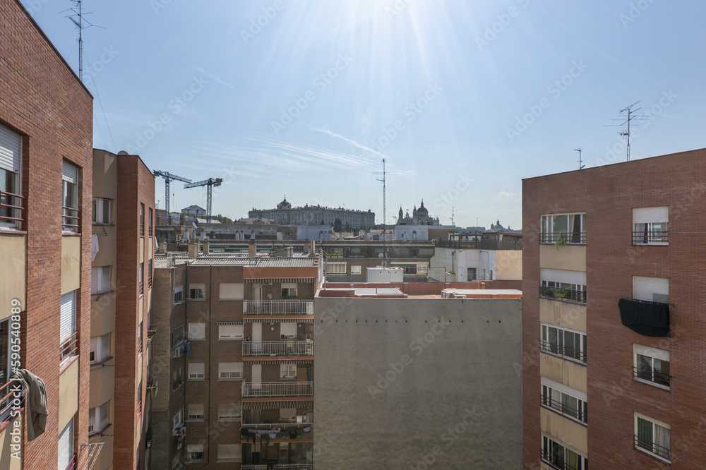 Block patio with facades of houses on a sunny day with the Royal Palace of Madrid in the background Block patio with facades of houses on a sunny day with the Royal Palace of Madrid in the background