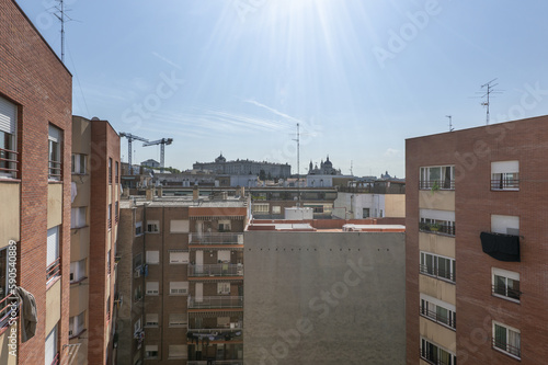 Block patio with facades of houses on a sunny day with the Royal Palace of Madrid in the background