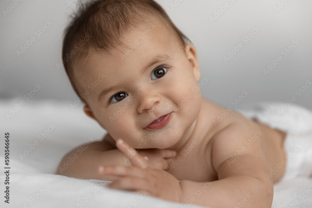 Portrait of happy newborn baby girl lies on a white blanket with cute smile in a selective focus Portrait of happy newborn baby girl lies on a white blanket with cute smile in a selective focus