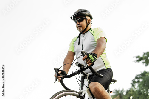 Adult man wearing a safety helmet driving of the city with his bicycle.