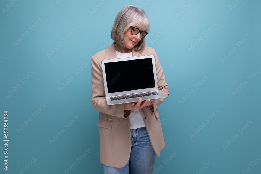close-up of a confident 60s middle-aged woman in a jacket with a laptop on a bright background with copy space close-up of a confident 60s middle-aged woman in a jacket with a laptop on a bright background with copy space