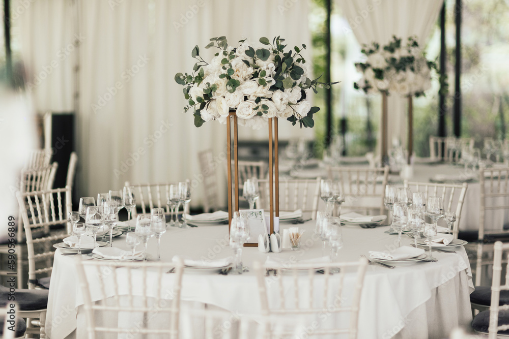 Wedding table in the restaurant decorated with white flowers. Table set for wedding or another catered event dinner. Wedding table in the restaurant decorated with white flowers. Table set for wedding or another catered event dinner.