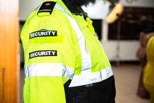 A female security guard is protecting an entrance of a private event. 