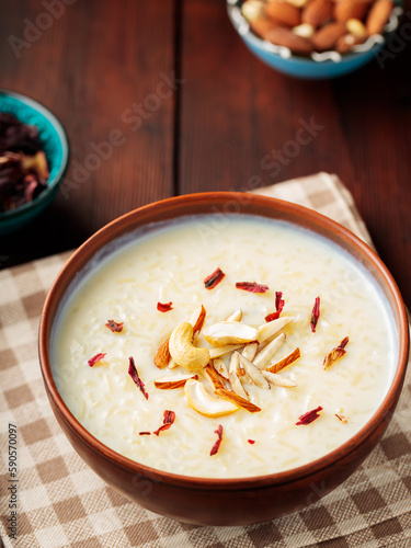 Rice pudding served in clay bowl. Indian rice kheer with nuts on a wooden background. Popular Ramadan dish. Top view