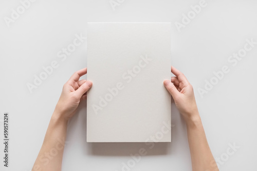 female hands hold empty a4 cardboard banner on white background. empty space for text