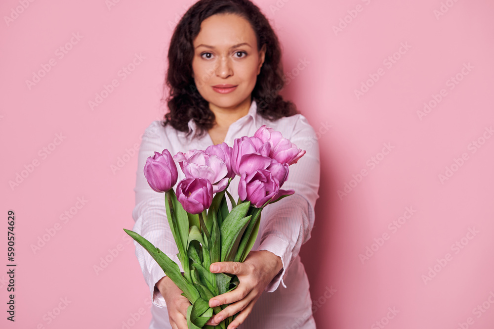 Details on beautiful purple tulips in the hands of charming middle-aged woman, holding out at camera a bouquet for festive occasion. Happy Teacher's, Mother's and International Women's Day concept